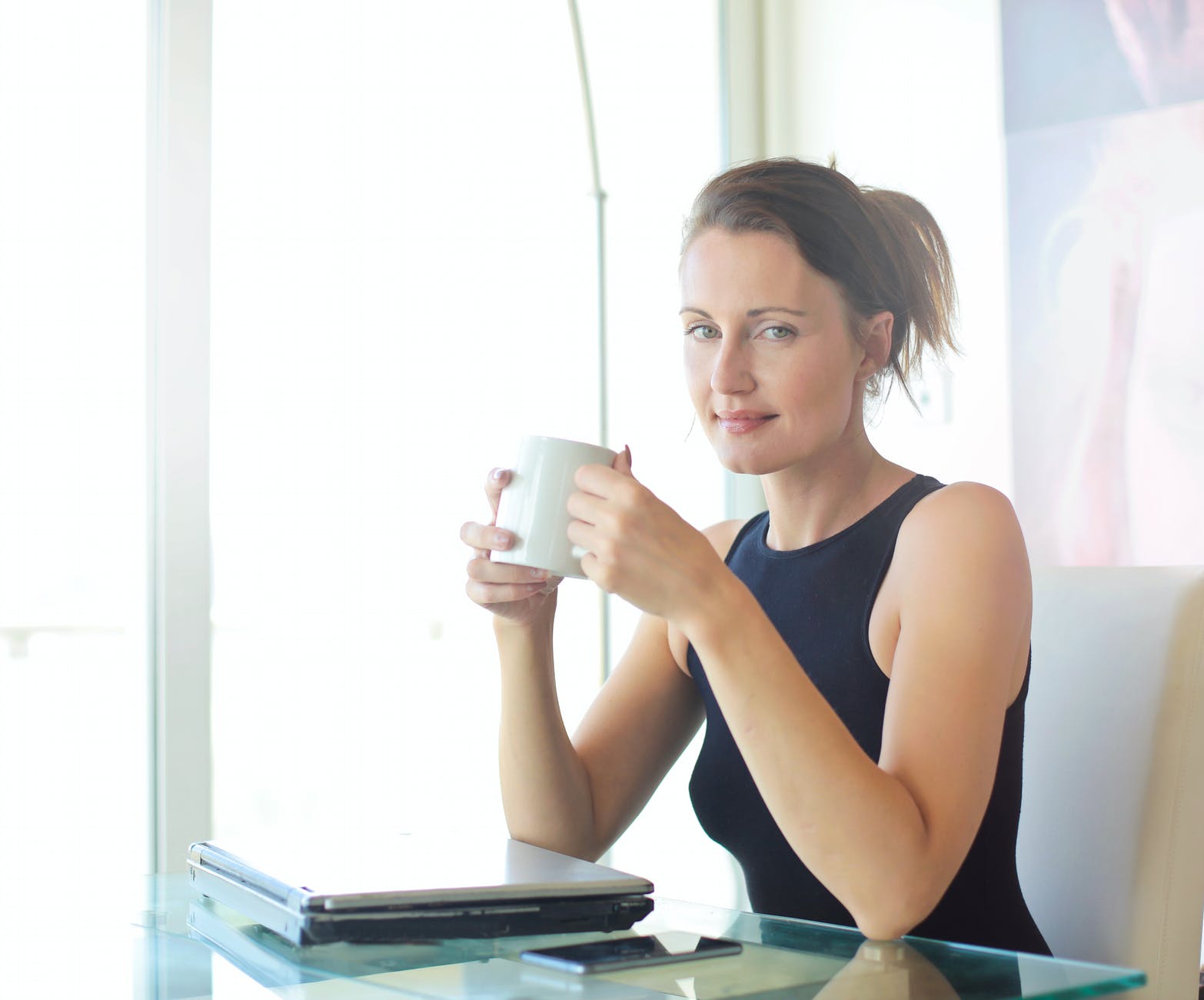 woman in black tank top holding white ceramic cup