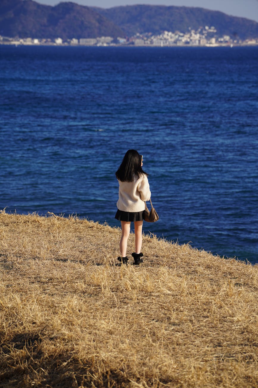 woman stands by the ocean on a sunny day